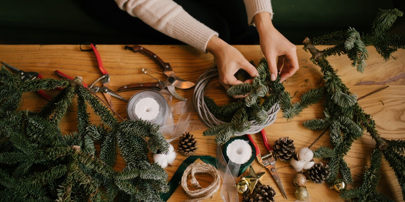 Person making a wreath using greenery and pine cones