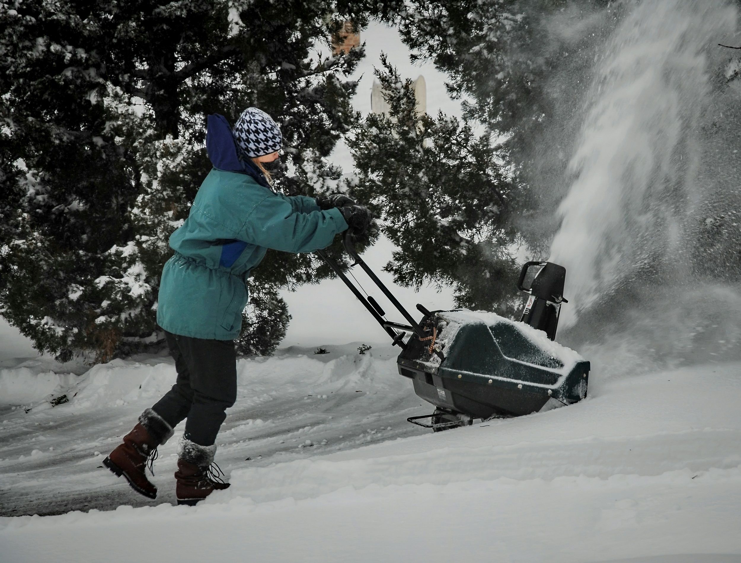 Person using a snow blower outside in winter conditions