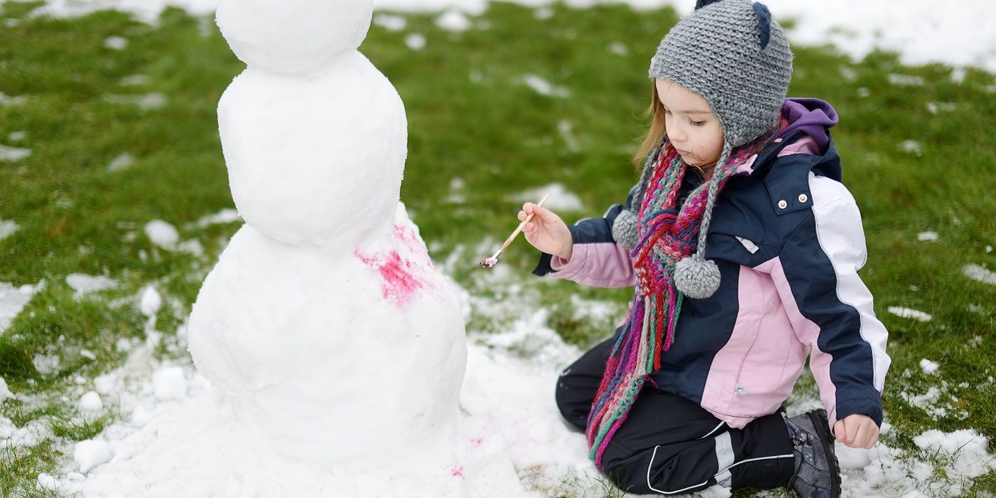 Young person painting on snow with paintbrush