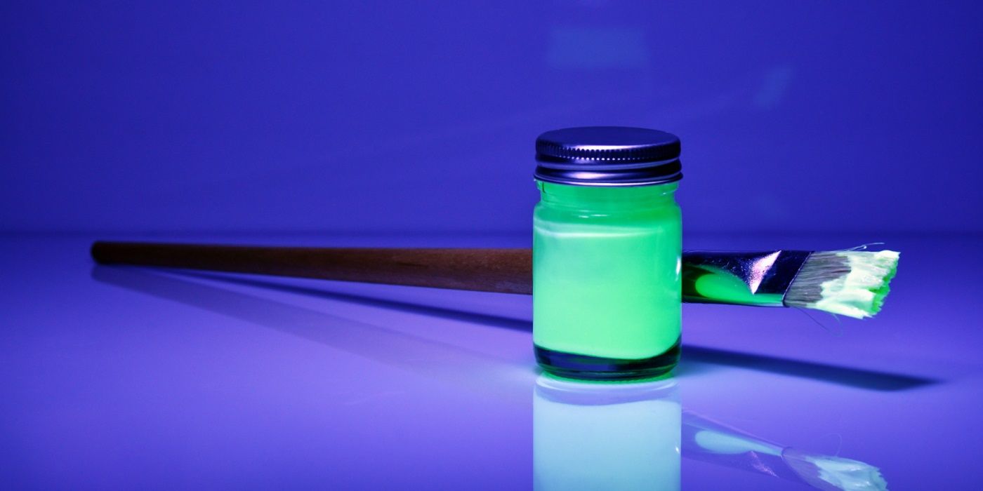 Glow in the dark paint jar and brush on a blue background