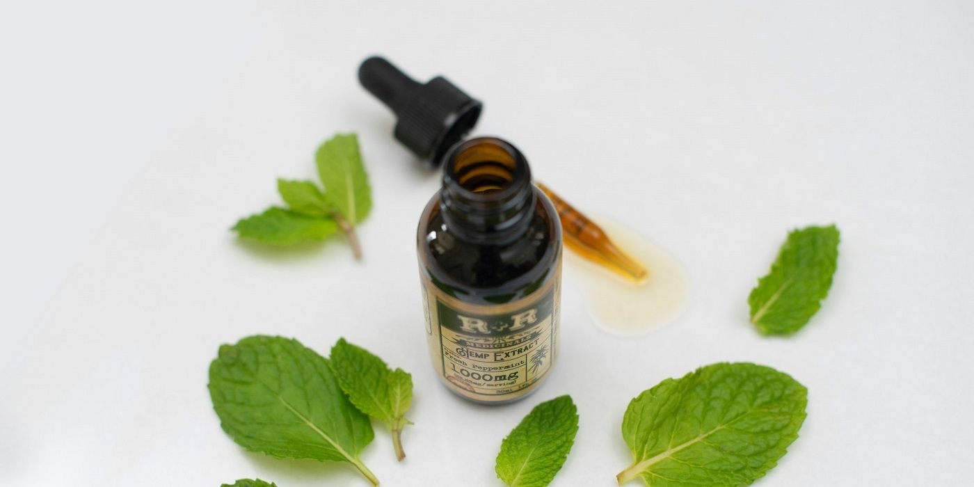 Peppermint oil bottle with dropper and leaves on a white table