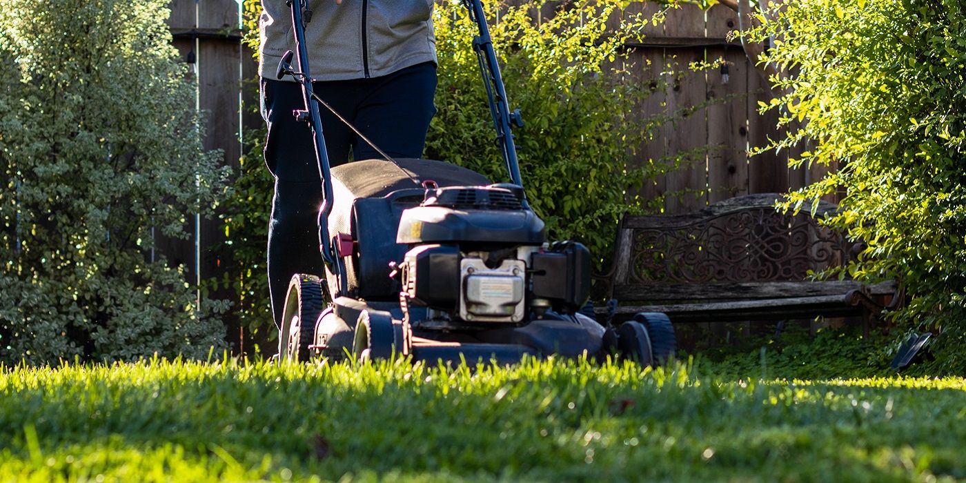 Person pushing a lawnmower across a lawn