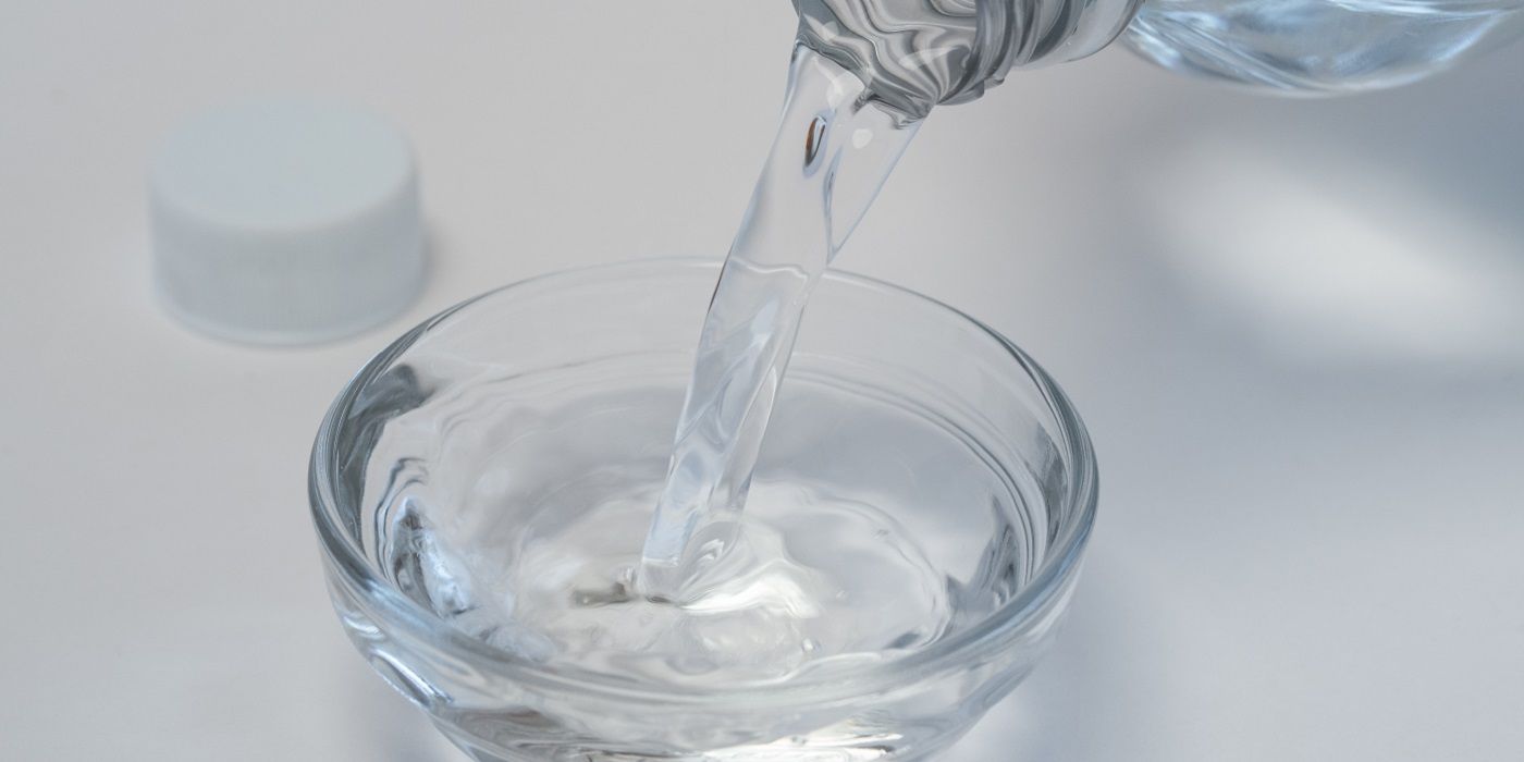 Pouring white vinegar into a clear glass bowl