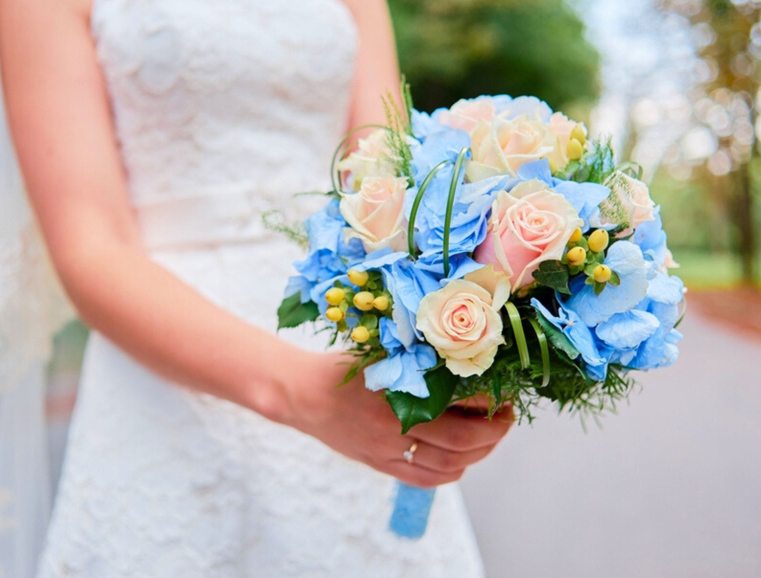Bride holding bouquet of pink roses and blue-toned flowers