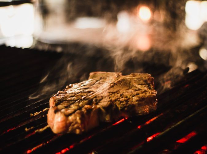 A piece of steak on a grill at night