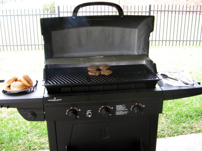 Gas grill with burgers on a grill grate