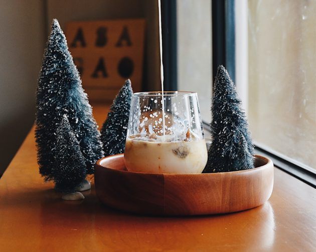 A glass of milk near small christmas trees