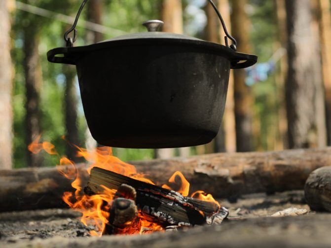 A black dutch oven over a campfire
