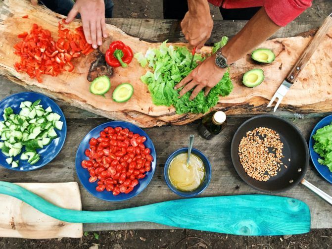 People cutting veggies on a wooden table
