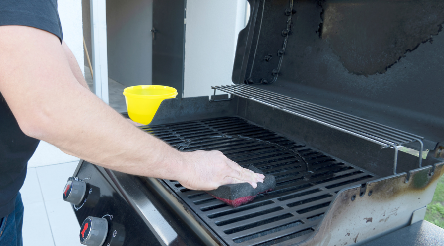 The male hand cleans the black grill with a soft brush